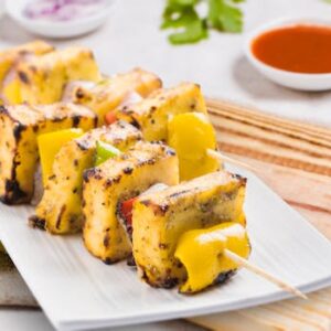 Tasty grilled paneer tikka skewers served on a plate with sauces, perfect for an Indian cuisine experience.